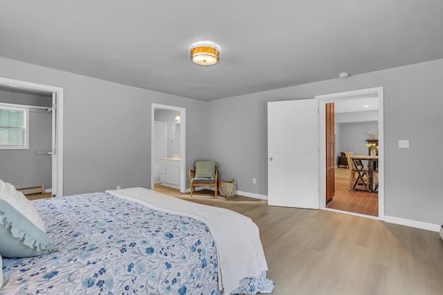 bedroom with connected bathroom, hardwood / wood-style floors, and a baseboard radiator