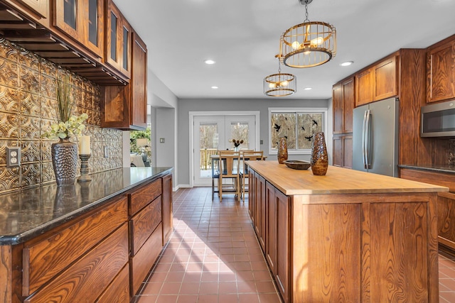 kitchen with wooden counters, decorative backsplash, a kitchen island, stainless steel appliances, and a chandelier