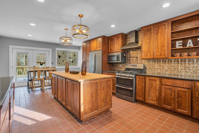 kitchen with stainless steel appliances, an inviting chandelier, plenty of natural light, and wall chimney exhaust hood