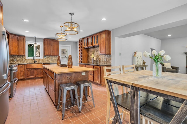 kitchen with pendant lighting, backsplash, an inviting chandelier, stainless steel stove, and a kitchen island