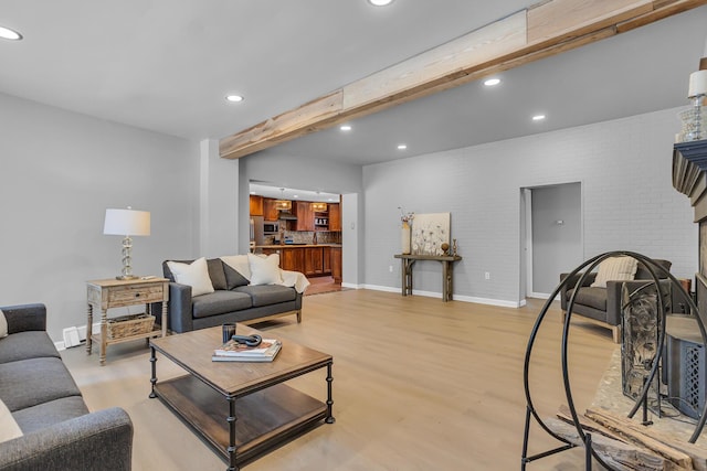 living room with light hardwood / wood-style flooring, beamed ceiling, and a baseboard heating unit