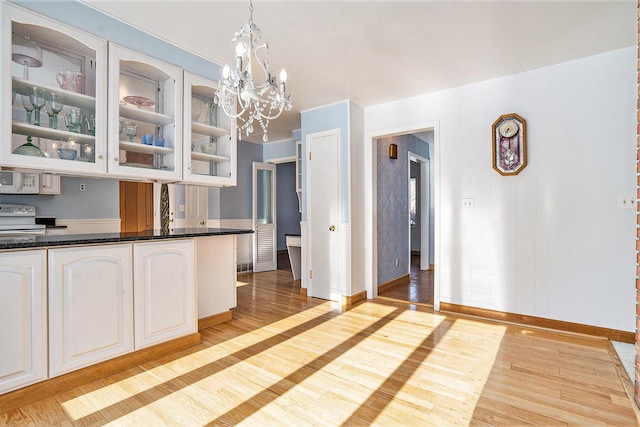 kitchen featuring white cabinets, a chandelier, hanging light fixtures, light hardwood / wood-style floors, and white appliances