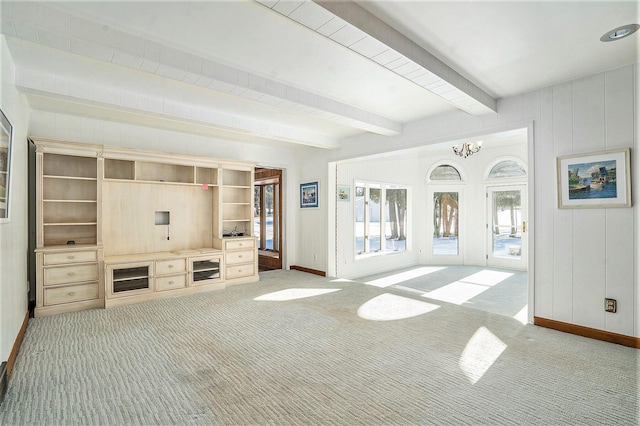 unfurnished living room with light carpet, beamed ceiling, and an inviting chandelier