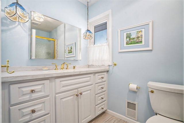 bathroom with hardwood / wood-style flooring, vanity, a shower with shower door, and toilet