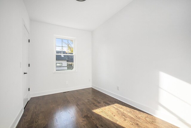 unfurnished room featuring vaulted ceiling and dark hardwood / wood-style floors