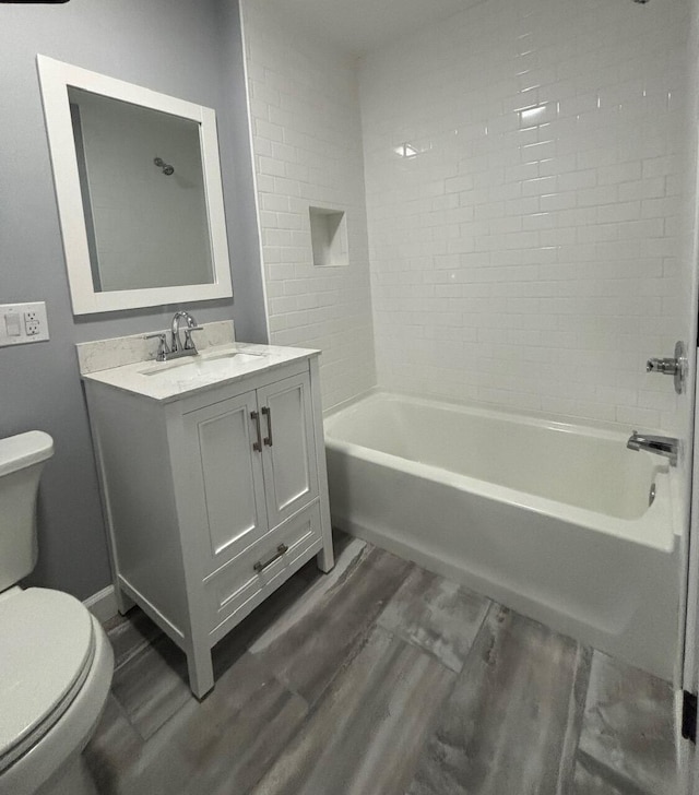 full bathroom featuring vanity, hardwood / wood-style floors, tiled shower / bath, and toilet