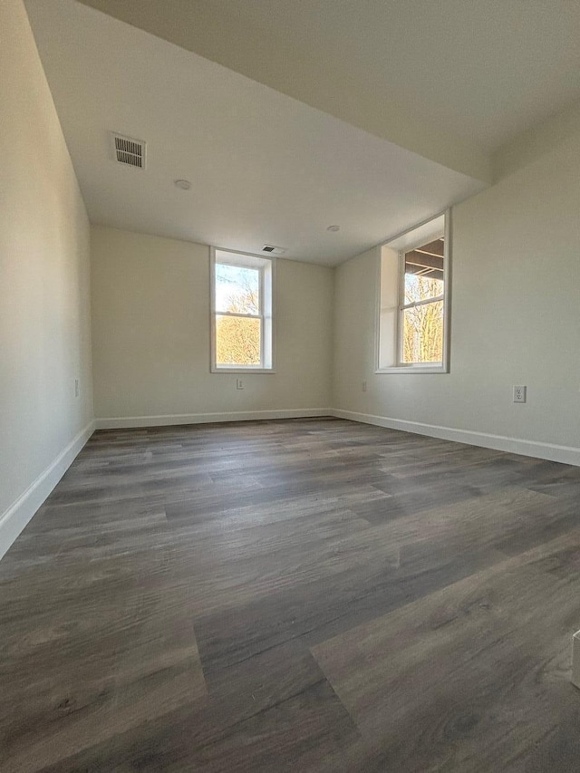 empty room with dark hardwood / wood-style floors and a wealth of natural light