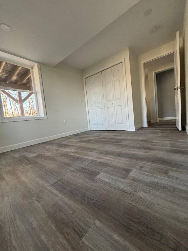 unfurnished bedroom featuring lofted ceiling with beams, dark hardwood / wood-style floors, and a closet