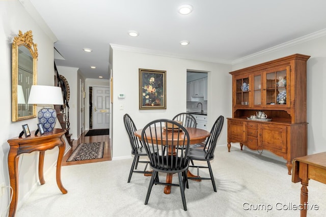 carpeted dining space with ornamental molding and sink