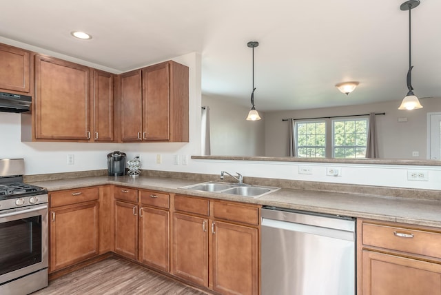 kitchen with decorative light fixtures, sink, stainless steel appliances, and exhaust hood