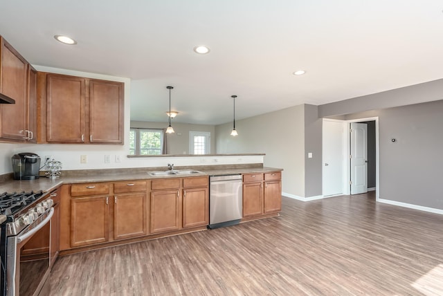 kitchen featuring pendant lighting, sink, stainless steel appliances, and light hardwood / wood-style flooring