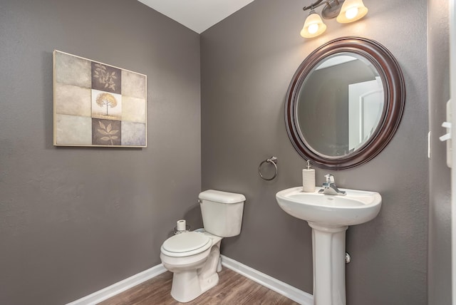 bathroom with toilet, wood-type flooring, and sink