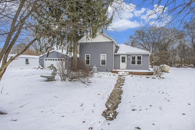 snow covered house featuring an outbuilding and a garage