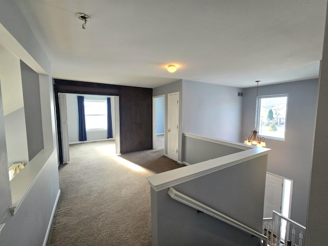 corridor featuring carpet flooring and an inviting chandelier