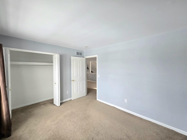 unfurnished bedroom featuring light carpet and a closet