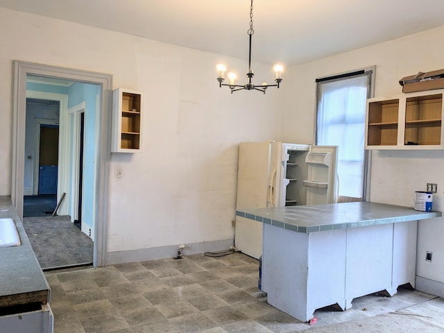 kitchen with tile counters, hanging light fixtures, a notable chandelier, kitchen peninsula, and white cabinets