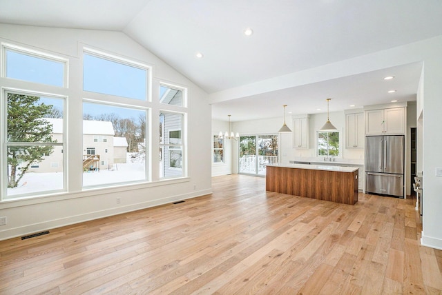 kitchen featuring a center island, hanging light fixtures, light hardwood / wood-style floors, high end fridge, and white cabinets