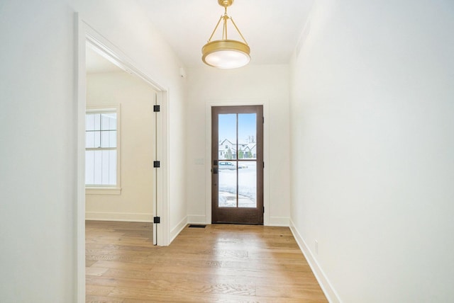 foyer with a wealth of natural light, light hardwood / wood-style flooring, and french doors