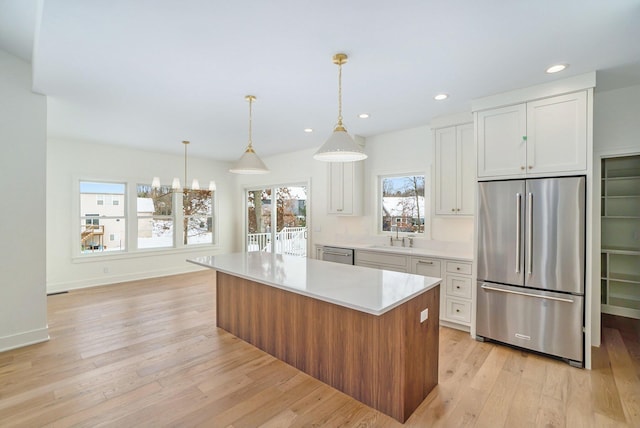 kitchen featuring stainless steel appliances, pendant lighting, light hardwood / wood-style flooring, white cabinets, and a center island