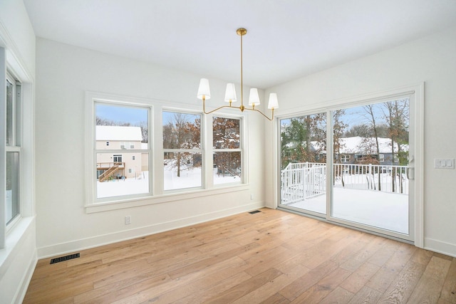 unfurnished dining area with light hardwood / wood-style flooring and an inviting chandelier