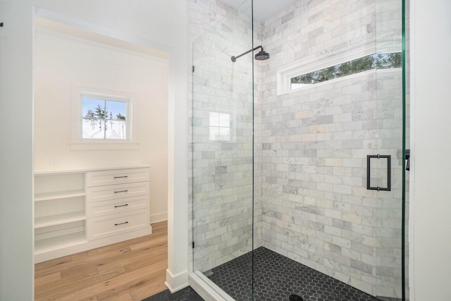 bathroom with hardwood / wood-style floors, a shower with door, and a wealth of natural light