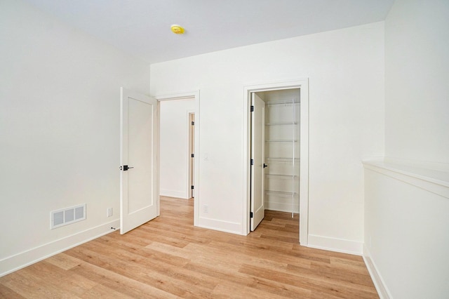 unfurnished bedroom with light hardwood / wood-style floors, a spacious closet, and a closet