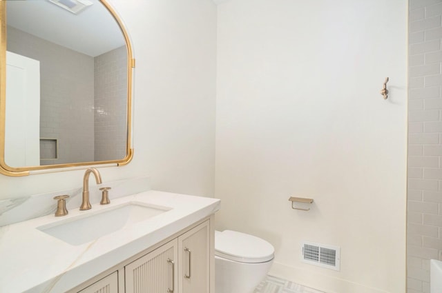 bathroom featuring tiled shower, vanity, and toilet