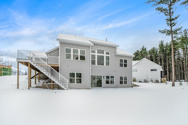 snow covered rear of property with a deck