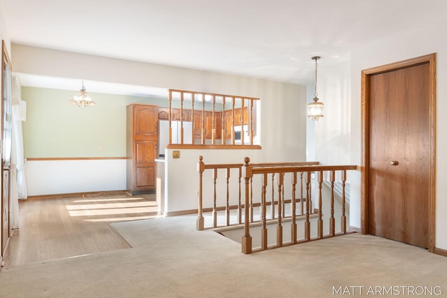 hall featuring light colored carpet and a chandelier