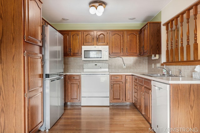 kitchen with backsplash, light hardwood / wood-style floors, white appliances, and sink