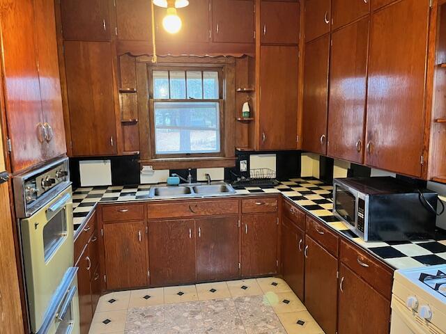 kitchen featuring light tile patterned flooring, stainless steel oven, white range with electric cooktop, and sink