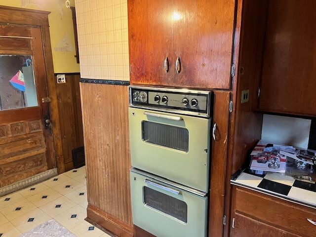 kitchen featuring double oven and wooden walls