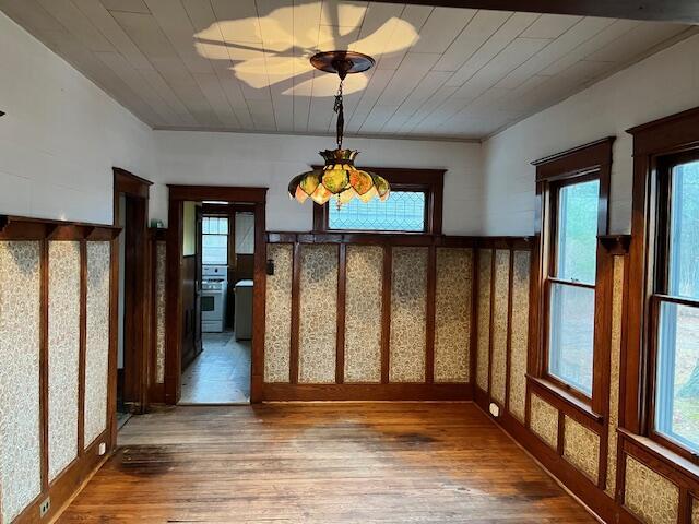 unfurnished dining area featuring hardwood / wood-style flooring, a notable chandelier, and wood ceiling