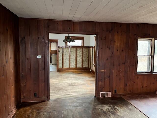 hallway featuring a chandelier, hardwood / wood-style flooring, and wooden walls