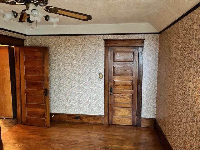 empty room with dark hardwood / wood-style floors, ceiling fan, crown molding, and a textured ceiling