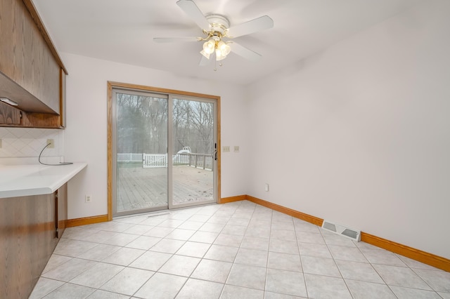 unfurnished dining area with ceiling fan and light tile patterned floors