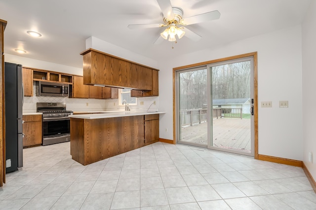 kitchen featuring ceiling fan, decorative backsplash, light tile patterned floors, kitchen peninsula, and stainless steel appliances