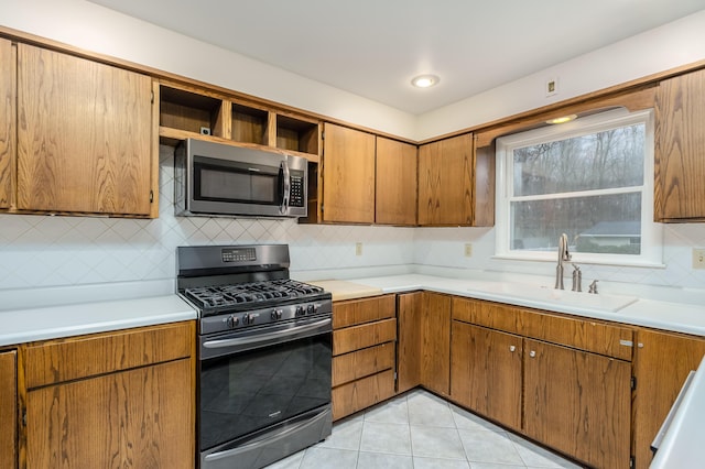 kitchen featuring light tile patterned flooring, appliances with stainless steel finishes, backsplash, and sink