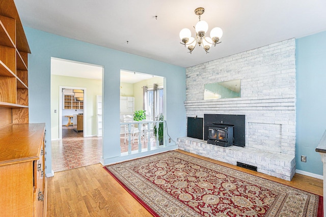 living room featuring a chandelier, wood-type flooring, and a wood stove