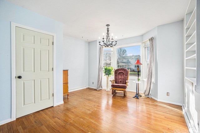 unfurnished room with a chandelier, a baseboard radiator, and light hardwood / wood-style flooring