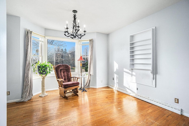 sitting room featuring built in features, a baseboard radiator, a notable chandelier, and hardwood / wood-style flooring