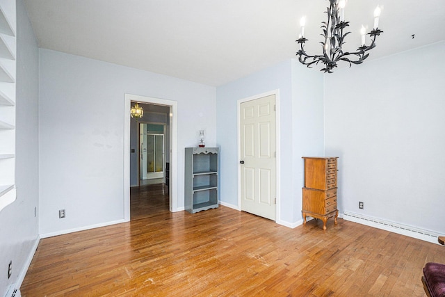 unfurnished room featuring a notable chandelier, light wood-type flooring, and baseboard heating