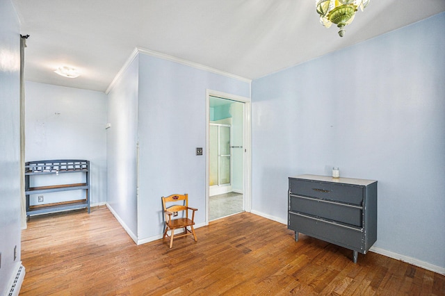 corridor featuring ornamental molding, baseboard heating, and light hardwood / wood-style flooring