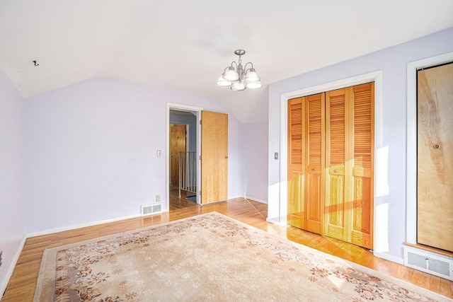 interior space featuring hardwood / wood-style floors, a chandelier, and vaulted ceiling