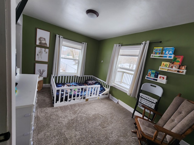 carpeted bedroom featuring multiple windows and a nursery area