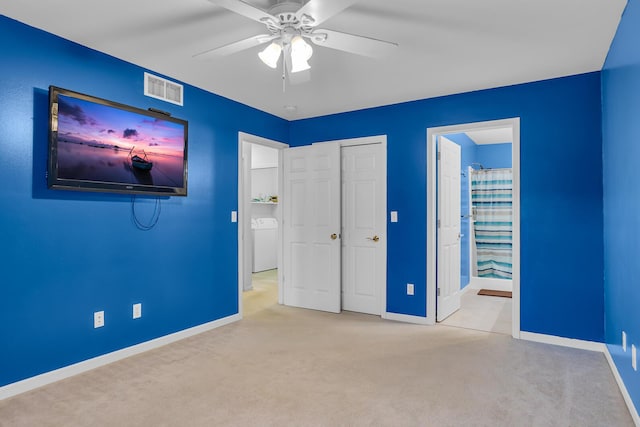 unfurnished bedroom with ceiling fan, light colored carpet, washer / clothes dryer, and connected bathroom