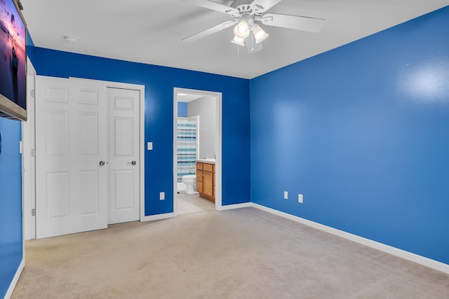 unfurnished bedroom featuring ensuite bathroom, a closet, ceiling fan, and light colored carpet