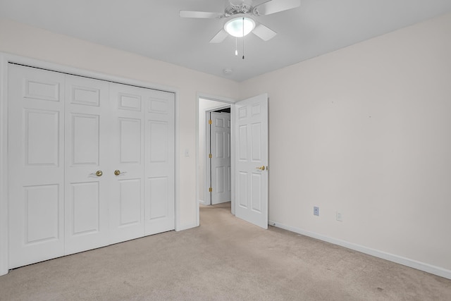 unfurnished bedroom featuring ceiling fan, light carpet, and a closet