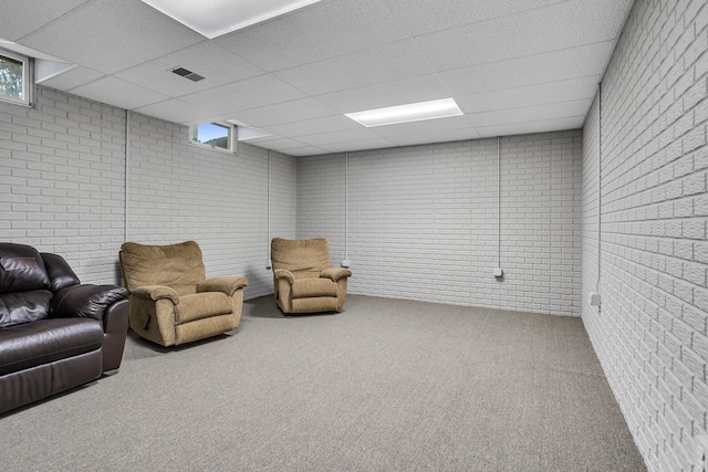 sitting room with carpet flooring, a drop ceiling, and brick wall