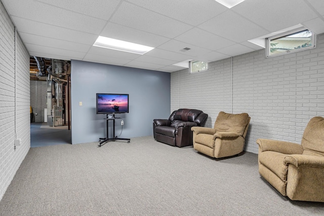 living room with carpet, a paneled ceiling, brick wall, and heating unit